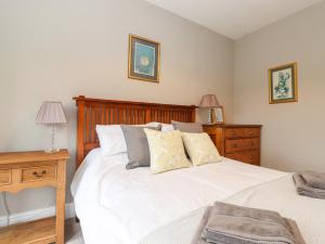 a bedroom with a white bed with a wooden headboard at Farnelea in Chathill