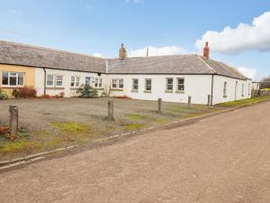 an empty road in front of a white house at Farnelea in Chathill