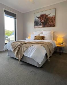 a bedroom with a large bed with a bull painting on the wall at Modern home away from home in Mansfield
