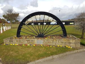 a large wheel sign in a field with flowers at Grange Villa Amethyst 3 Bed House near Chester le Street, sleeps 6 Guests in Chester-le-Street