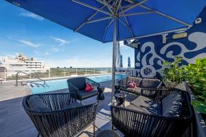 eine Terrasse mit Stühlen, einem Sonnenschirm und einem Pool in der Unterkunft Ocean Drive Apartments with Rooftop Pool, South Beach, Miami in Miami Beach