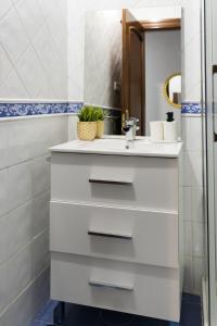 ein weißes Badezimmer mit einem Waschbecken und einem Spiegel in der Unterkunft MyHouseSpain - Playa de poniente, con vistas al mar y parking gratuito in Gijón
