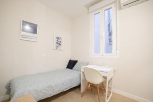 a bedroom with a bed and a desk and a window at MyHouseSpain - Acogedor piso con patio en Chamberi in Madrid