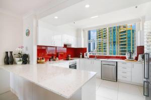 een witte keuken met rode kasten en een groot raam bij Gold Coast 600 Fan Fav in Gold Coast
