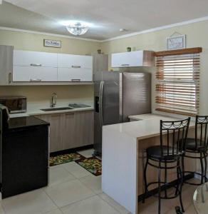 uma cozinha com um frigorífico e um balcão com cadeiras em Comfy Seascape Retreat near Kingston Airport em Kingston