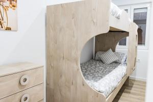 a wooden bunk bed in a room with a dresser at MyHouseSpain - Piso en centro Gijón a pocos minutos de las playas in Gijón