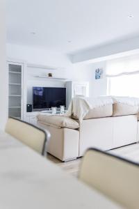 a white living room with a couch and a tv at MyHouseSpain - Piso en centro Gijón a pocos minutos de las playas in Gijón