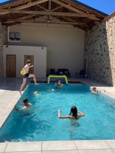 grupa ludzi bawiących się w basenie w obiekcie Gite de la Foye - La Couleur des prés w mieście Combrand
