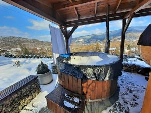 bañera de hidromasaje en una terraza con nieve en el suelo en Chata Panorama en Stróża