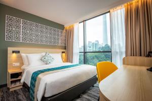 a hotel room with a bed and a desk and a window at Santa Grand Signature Kuala Lumpur in Kuala Lumpur