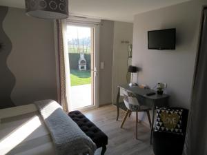 Habitación con cama, escritorio y ventana. en Chambres d'Hotes La Maison Neuve, en Saint-Loup