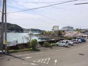 una calle con coches estacionados junto a un cuerpo de agua en ゲストハウスさくら Guesthouse Sakura, en Sukumo