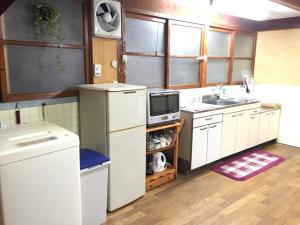宿毛市にあるゲストハウスさくら Guesthouse Sakuraのキッチン(白い冷蔵庫、シンク付)