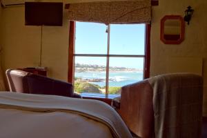 a bedroom with a large window with a view of the ocean at Agulhas Country Lodge in Agulhas