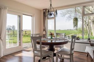 een eetkamer met een tafel, stoelen en ramen bij Akkerhorst boerderij Lollum in Friesland. in Lollum