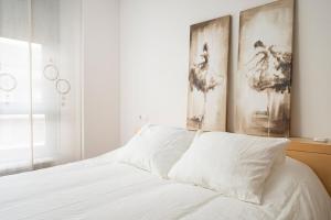 a bedroom with a white bed with two paintings on the wall at MyHouseSpain - Fantastico piso cerca del centro in Oviedo
