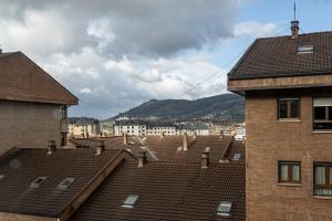 a view of roofs of buildings with mountains in the background at MyHouseSpain - Fantastico piso cerca del centro in Oviedo
