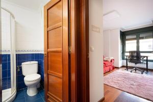 a bathroom with a toilet and a wooden door at MyHouseSpain - Fantastico piso cerca del centro in Oviedo