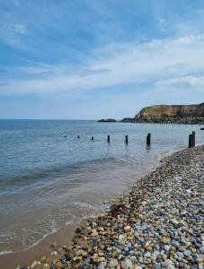 a beach with a rocky shoreline and the ocean at The Light House in Seaham