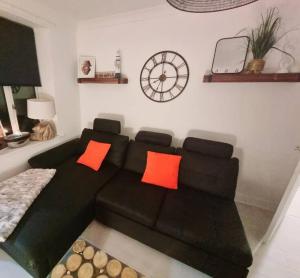 sala de estar con sofá negro y almohadas de color naranja en The Light House, en Seaham