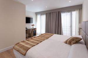 Hotel SAIOLA في كامبرودون: غرفة نوم مع سرير أبيض كبير ومكتب