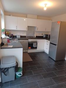 a kitchen with white cabinets and a gray tile floor at Spacious Ensuite King Room Private Neighbourhood Free Parking Space in Oldham