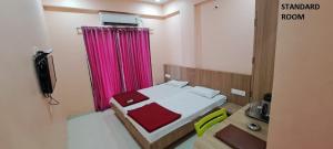 a small bedroom with a bed and a pink curtain at Hotel Aaditya Palace in Bhusāwal