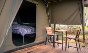a tent with two chairs and a bed in it at Bike Forge Glamping in Tulbagh