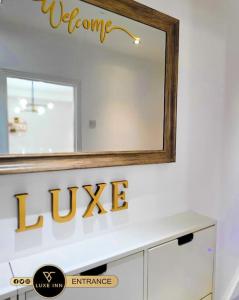 un miroir sur un mur au-dessus d'un comptoir de salle de bains dans l'établissement Luxury, 4 Bedroom House, FREE Parking, Borehamwood, à Borehamwood