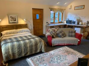 a bedroom with a bed and a couch and a chair at Stybeck Farm in Thirlmere
