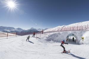 un grupo de personas esquiando por una pista cubierta de nieve en Hotel Harmony Tigilou Belalp, en Belalp