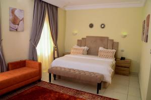 1 dormitorio con cama, sofá y ventana en House 24 en Abuja