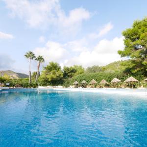 a swimming pool with umbrellas and a beach at Camping Azahar in Benicàssim