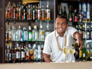 un hombre vertiendo una copa de vino en un bar en Novotel Suva Lami Bay en Suva