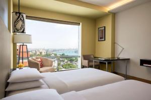 a hotel room with two beds and a large window at Hyatt Regency Ahmedabad in Ahmedabad