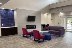 a living room with a couch and chairs and a tv at La Quinta Inn and Suites by Wyndham - Schertz in Schertz