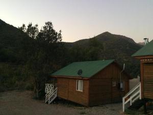 a small cabin with a green roof with mountains in the background at Cabañas con bajada al río in Guayacán
