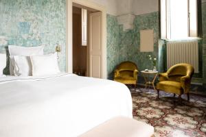 a bedroom with a white bed and two chairs at Casa a Corte, Nardò in Nardò