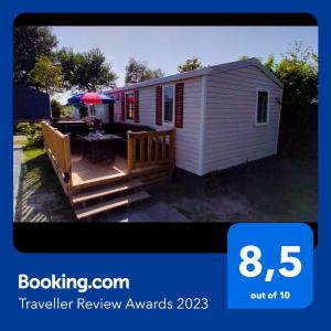 a tiny house with a porch and a deck at BJ Chalets - Robbengat 68 - Gezellige, kindvriendelijke chalet op vakantiepark Lauwersoog! Vroege incheck! in Lauwersoog