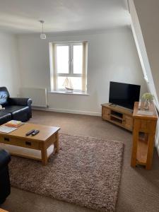 a living room with a couch and a tv at Yare Quays River View in Great Yarmouth