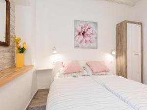 a white bedroom with a large bed with pink pillows at Studio Apartment Sisi in Opatija