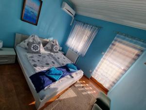 Schlafzimmer mit einem Bett mit blauen Wänden und einem Fenster in der Unterkunft Balaton House in Balatonboglár
