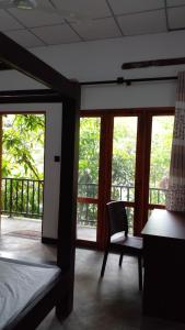 a bedroom with a bed and a desk and windows at Nageran Homestay in Dambulla