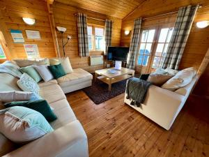 een woonkamer met witte banken en een televisie bij Reeds Lodge, Lake Pochard in South Cerney