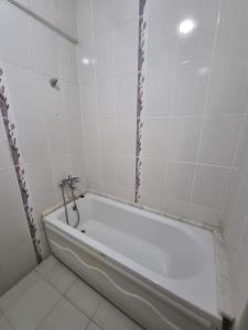 a white bath tub in a bathroom with white tiles at Thermal Orkide Pansiyon in Yalova