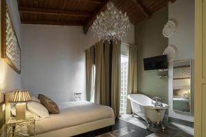 a bedroom with a bed and a tub and a chandelier at Le Meraviglie di Alice in Cagliari