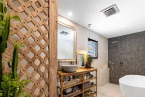 a bathroom with a tub and a sink and a mirror at Palm Springs Vibe - Gorgeous Large Home, Superb Location in Noosa Heads +15 photos