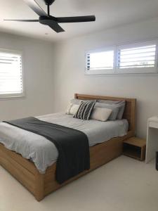 a bedroom with a bed with a ceiling fan at LA Inspired, Gorgeous Spacious Family Home, Superb Location in Noosa Heads