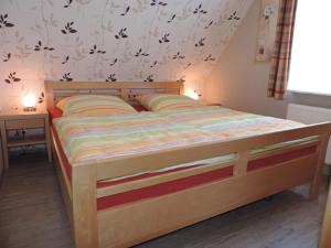Una cama de madera en un dormitorio con una pared con mariposas. en Ferienhaus Uhlenhorst, en Büsumer Deichhausen