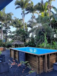 una piscina con una mesa frente a las palmeras en Les Gîtes de la Lézarde, en Petit-Bourg